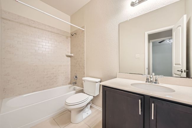 Bathroom featuring shower combination, vanity, tile patterned floors, and a textured wall | Image 25
