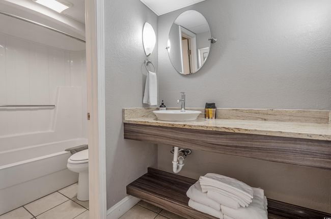 Bathroom featuring tile patterned flooring, shower / bath combination, and a textured wall | Image 7