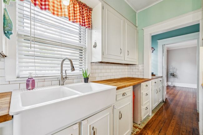 Kitchen with butcher block counters, decorative backsplash, dark wood-style floors, healthy amount of natural light, and ornamental molding | Image 13