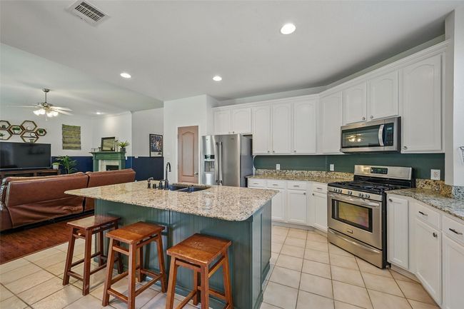 Kitchen with stainless steel appliances, a sink, light tile patterned floors, open floor plan, and recessed lighting | Image 11
