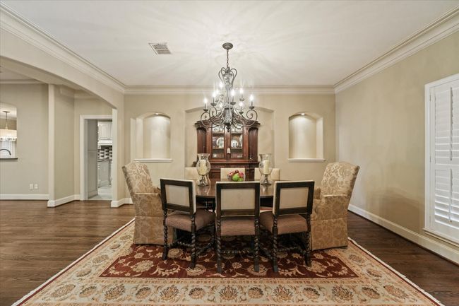 Dining space with a chandelier, arched walkways, wood finished floors, baseboards, and crown molding | Image 8