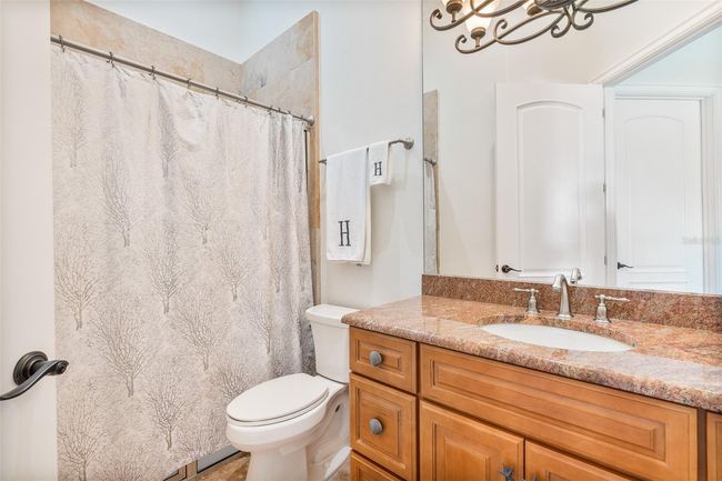 Bright, stylish, and effortlessly functional—this guest bathroom features warm natural stone countertops, custom cabinetry, and a full tub-shower combo, offering comfort and convenience for visitors or family alike. | Image 18