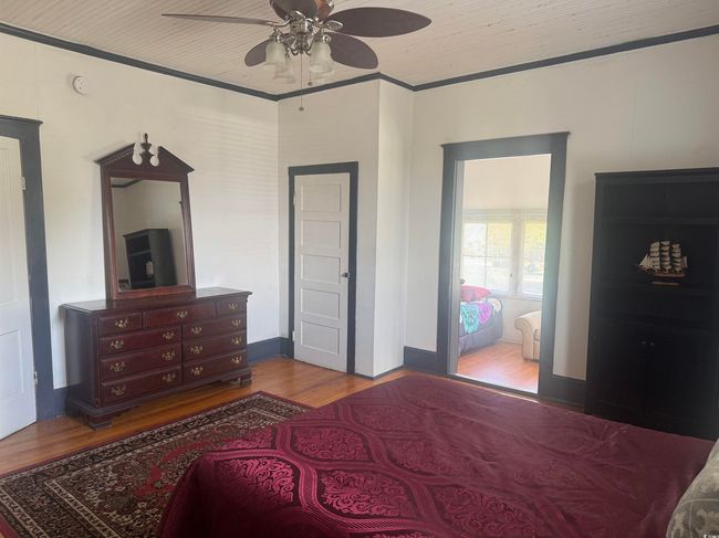 Bedroom featuring wood finished floors, a ceiling fan, and ornamental molding | Image 20