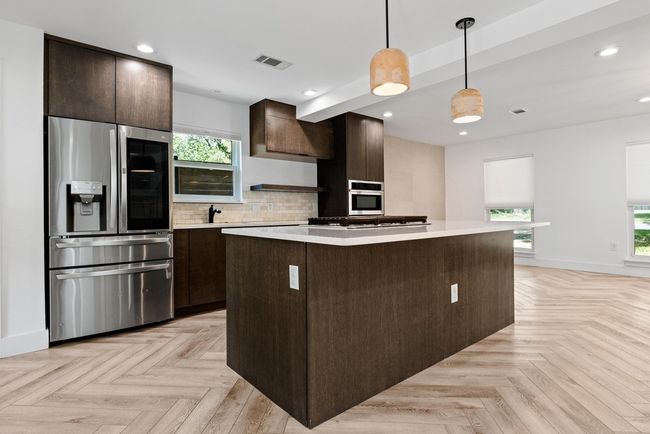 Kitchen featuring dark brown cabinets, stainless steel appliances, light countertops, and a kitchen island | Image 15