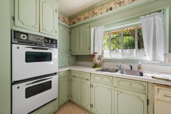 Kitchen with white double oven, dishwasher, light countertops, green cabinetry, and ornamental molding | Image 14