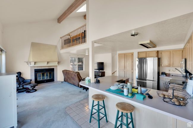 Kitchen featuring open floor plan, light brown cabinetry, freestanding refrigerator, a peninsula, and light carpet | Image 7