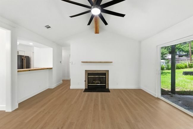 Unfurnished living room with light wood-style flooring, a ceiling fan, and a fireplace with flush hearth | Image 6