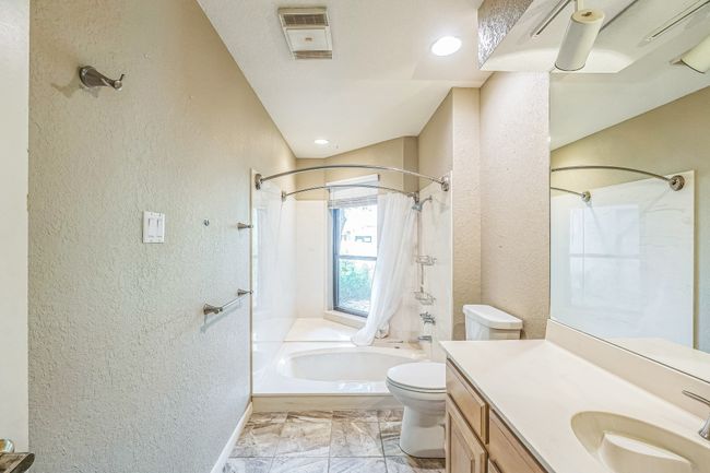 Bathroom featuring toilet, shower / tub combination, a textured wall, and vanity | Image 22