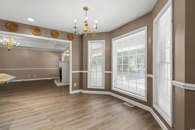 Unfurnished dining area with a chandelier, wood finished floors, and a fireplace with raised hearth | Image 12