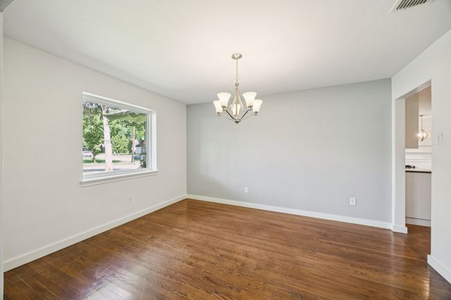 DINING ROOM Situated at Front of Home and Adjacent to Kitchen, Boasts Wide Doorways, Ovesized Picture Window With Views of Front Yard, Decorative Chandelier, Neutral Colors, and Wood Flooring | Image 5