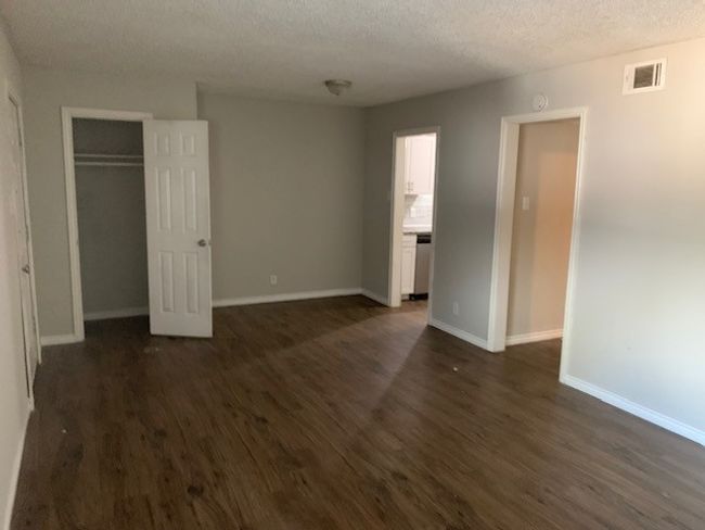 Unfurnished bedroom with dark wood-type flooring, baseboards, a textured ceiling, and a closet | Image 8