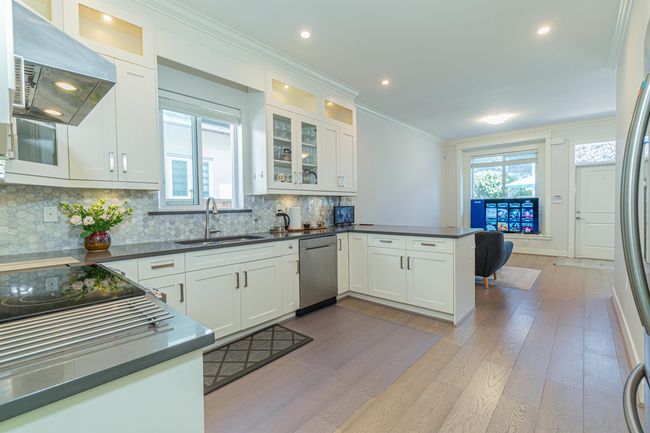 Kitchen with a sink, exhaust hood, appliances with stainless steel finishes, a peninsula, and dark countertops | Image 8