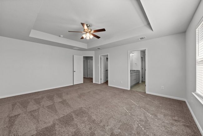 Unfurnished bedroom featuring a tray ceiling, carpet flooring, a spacious closet, and multiple windows | Image 24