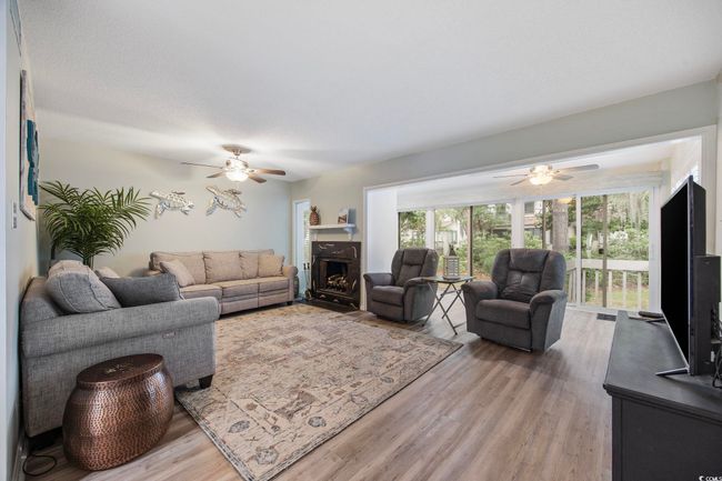 Living area featuring a ceiling fan, light wood-type flooring, and a fireplace | Image 19