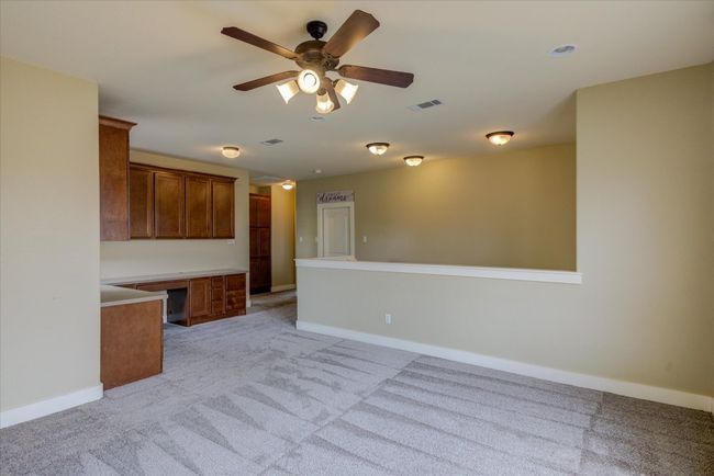 Gameroom featuring built-ins, a ceiling fan, light carpet, and built in study area | Image 24