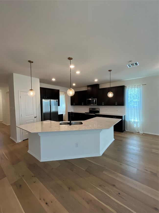 Kitchen featuring visible vents, decorative backsplash, fridge, a large island with sink, and a sink | Image 10