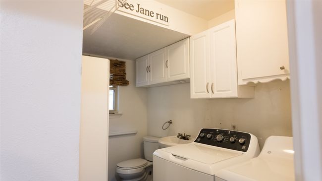 Clothes washing area with cabinet space, washer and dryer, and a sink | Image 18