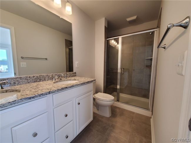 Bathroom with dark tile floors, double large vanity, a shower with shower door, and mirror | Image 29