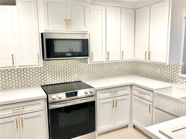 Kitchen with appliances with stainless steel finishes, light countertops, backsplash, and white cabinets | Image 7