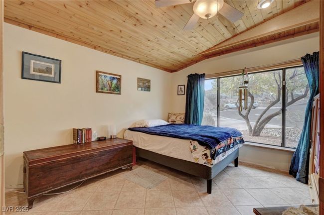 Bedroom with lofted ceiling, wooden ceiling, light tile patterned floors, and a ceiling fan | Image 49