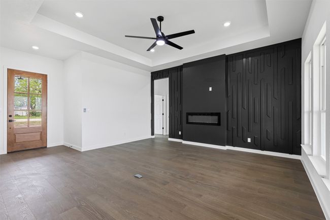 Unfurnished living room with ceiling fan, baseboards, dark wood-style floors, a tray ceiling, and recessed lighting | Image 12