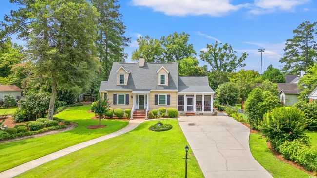Cape cod home featuring a sunroom, concrete driveway, a front lawn, a chimney, and a shingled roof | Image 27