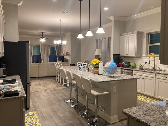Kitchen featuring crown molding, a kitchen breakfast bar, visible vents, and stainless steel appliances | Image 6