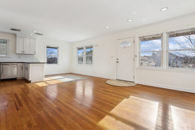 Unfurnished living room featuring baseboards, wood finished floors, and visible vents | Image 5