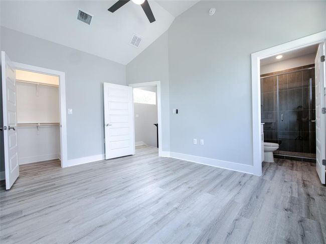 Unfurnished bedroom featuring high vaulted ceiling, light wood-type flooring, a closet, ensuite bath, and a ceiling fan | Image 17