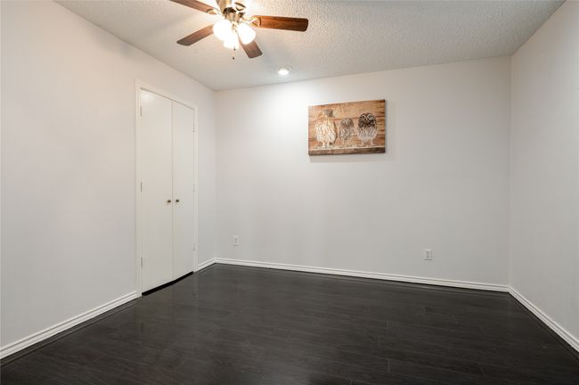 Spare room featuring a textured ceiling, ceiling fan, dark wood-style flooring, and baseboards | Image 22