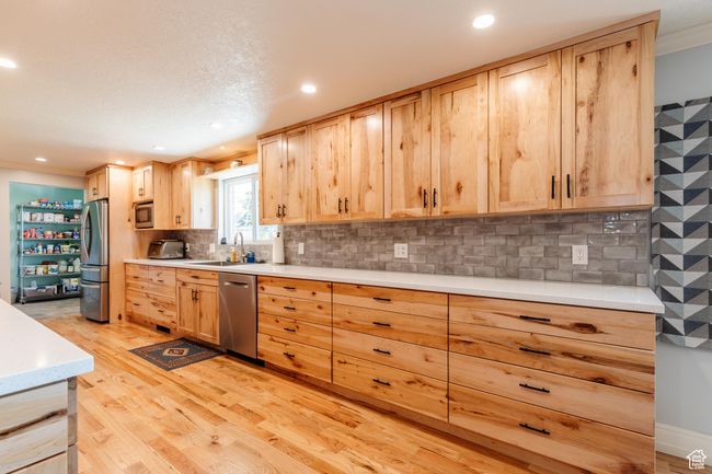 Kitchen with light wood finished floors, light brown cabinetry, recessed lighting, light countertops, and appliances with stainless steel finishes | Image 7