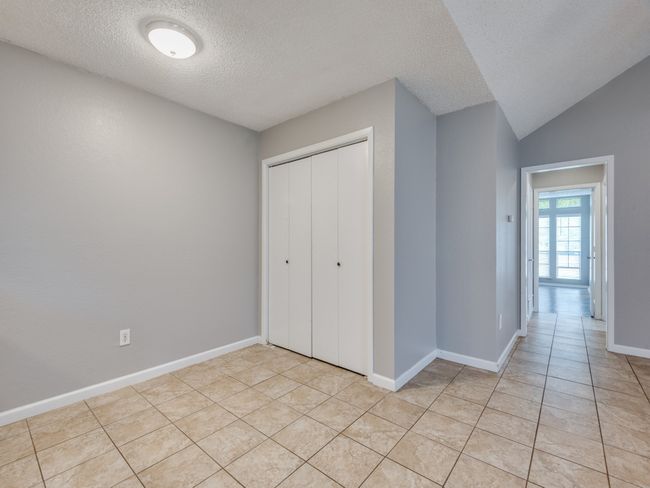 Unfurnished bedroom featuring a textured ceiling, light tile patterned floors, and a closet | Image 5