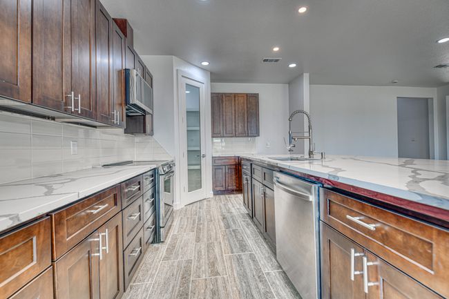 Kitchen featuring tasteful backsplash, light stone countertops, sink, light hardwood / wood-style floors, and stainless steel appliances | Image 16
