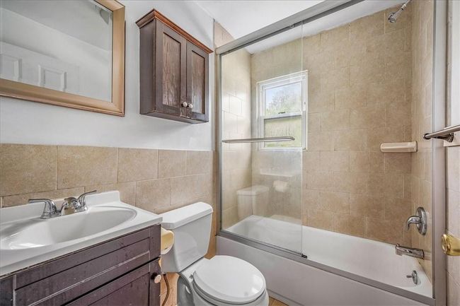 Full bathroom with tile walls, vanity, toilet, and enclosed tub / shower combo | Image 14