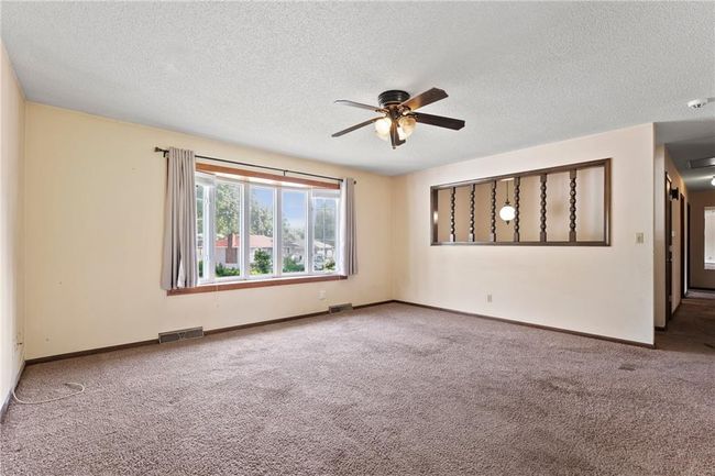 Empty room with carpet floors, ceiling fan, a textured ceiling, and baseboards | Image 6