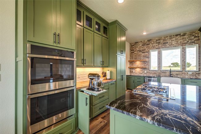 Kitchen featuring sink, green cabinets, stone countertops, and stainless steel appliances | Image 10