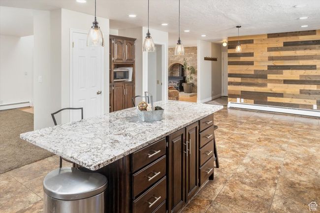 Kitchen with wood walls, a kitchen bar, and a kitchen island | Image 10