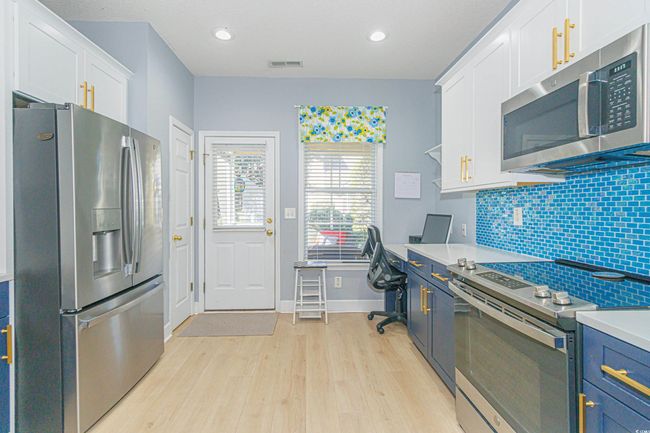 Kitchen with white cabinetry, blue cabinetry, stainless steel appliances, and light wood-type flooring | Image 12