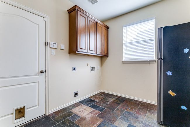 Laundry room with electric dryer hookup, stone tile floors, cabinet space, hookup for a washing machine, and hookup for a gas dryer | Image 17