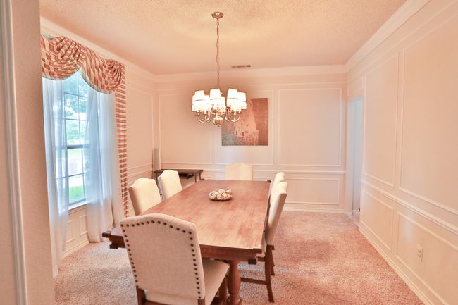 Dining room featuring a decorative wall, a chandelier, a textured ceiling, and light colored carpet | Image 11