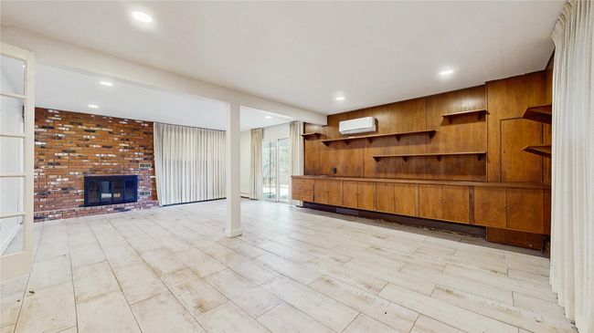 Unfurnished living room featuring recessed lighting, a fireplace, and an AC wall unit | Image 21