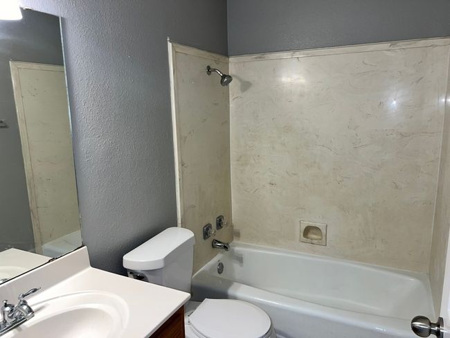 Full bathroom with a textured wall, washtub / shower combination, and vanity | Image 21
