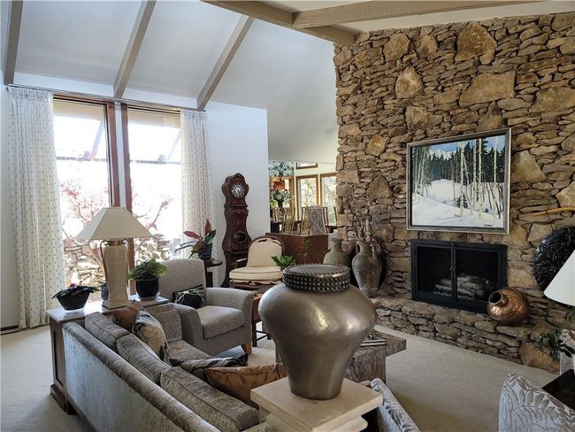 Carpeted living room featuring high vaulted ceiling, beam ceiling, and a fireplace | Image 5