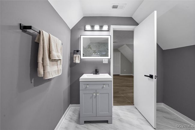 Primary Bedroom full Bathroom with vaulted ceiling, vanity, and marble finish flooring | Image 29