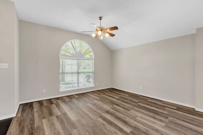 Extra large room with vaulted ceiling, baseboards, a ceiling fan, and wood finished floors | Image 6