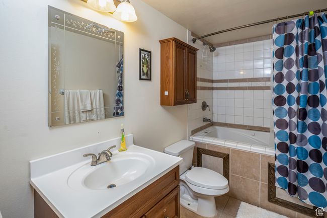 Bathroom with tile patterned floors, toilet, vanity, and tiled shower / bath | Image 13