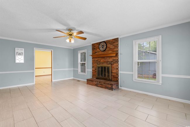 Unfurnished living room with ceiling fan, crown molding, a fireplace, and a textured ceiling | Image 11