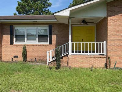 Entrance to property with a lawn and ceiling fan | Image 1