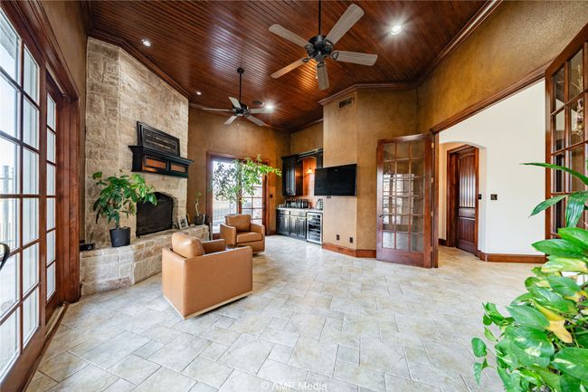 Living room featuring ceiling fan, a stone fireplace, wooden ceiling, and a towering ceiling | Image 7