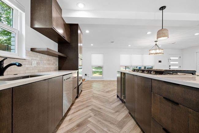 Kitchen with dark brown cabinets, open shelves, a sink, light countertops, and appliances with stainless steel finishes | Image 17